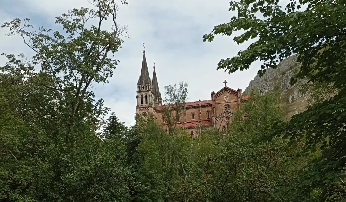 Basílica de Santa María la Real de Covadonga rodeada de árboles y montañas en Asturias