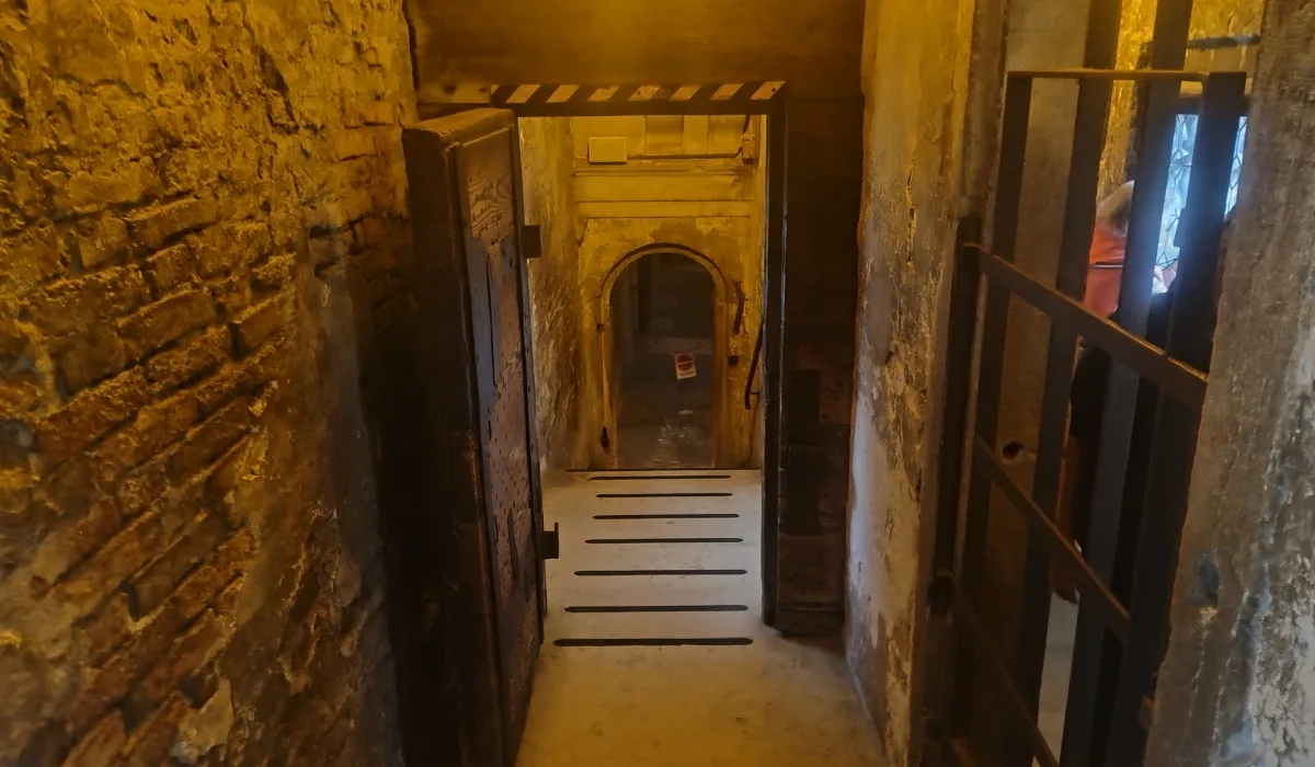 Corredor interior del Puente de los Suspiros del Palacio Ducal de Venecia, con muros de piedra y puertas reforzadas que conducen hacia las Prisiones Nuevas