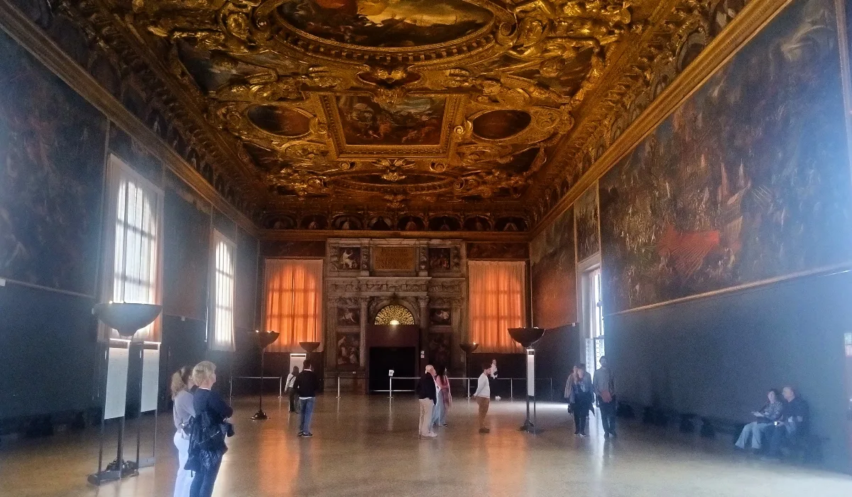 Vista de la majestuosa Sala del Gran Consejo del Palacio Ducal de Venecia, con su techo dorado y la Puerta del Paradiso al fondo, lugar donde se celebraban las asambleas de la nobleza veneciana.