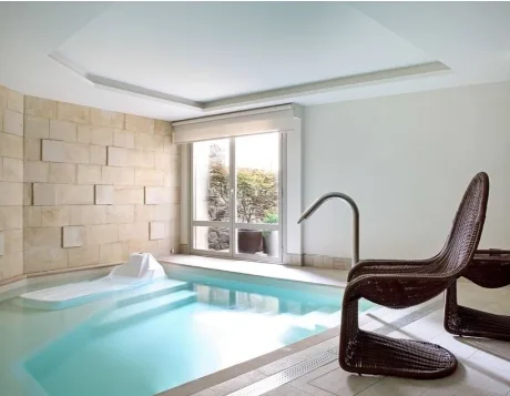 Piscina interior del Hotel Artesa Suites & Spa, con luz natural, pared de piedra y zona de relajación