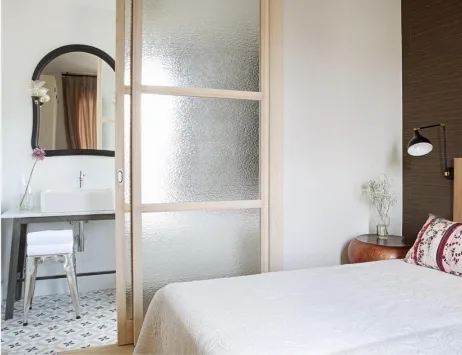Dormitorio del Hotel Artesa Suites & Spa con cama doble, puerta corredera hacia el baño y estilo acogedor y contemporáneo