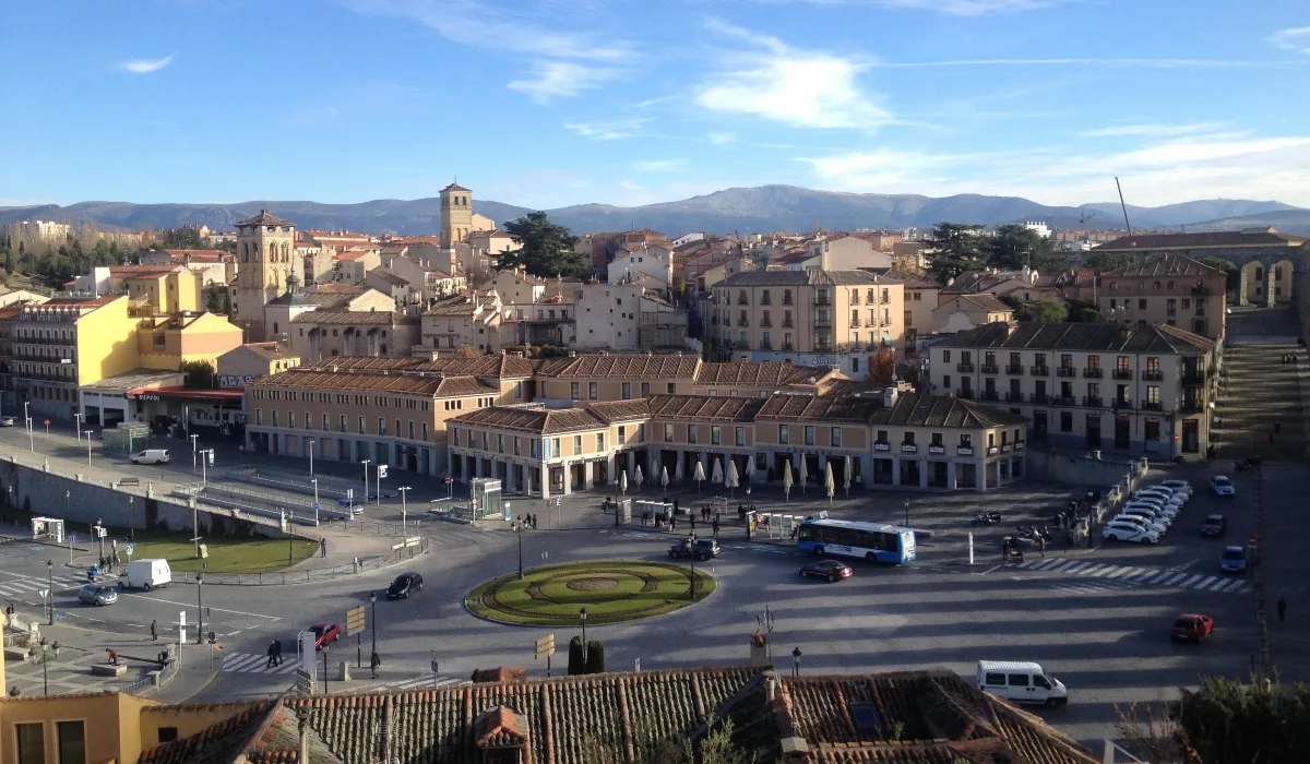 Vista panorámica del Azoguejo de Segovia, con la plaza, los tejados históricos y la Sierra de Guadarrama al fondo