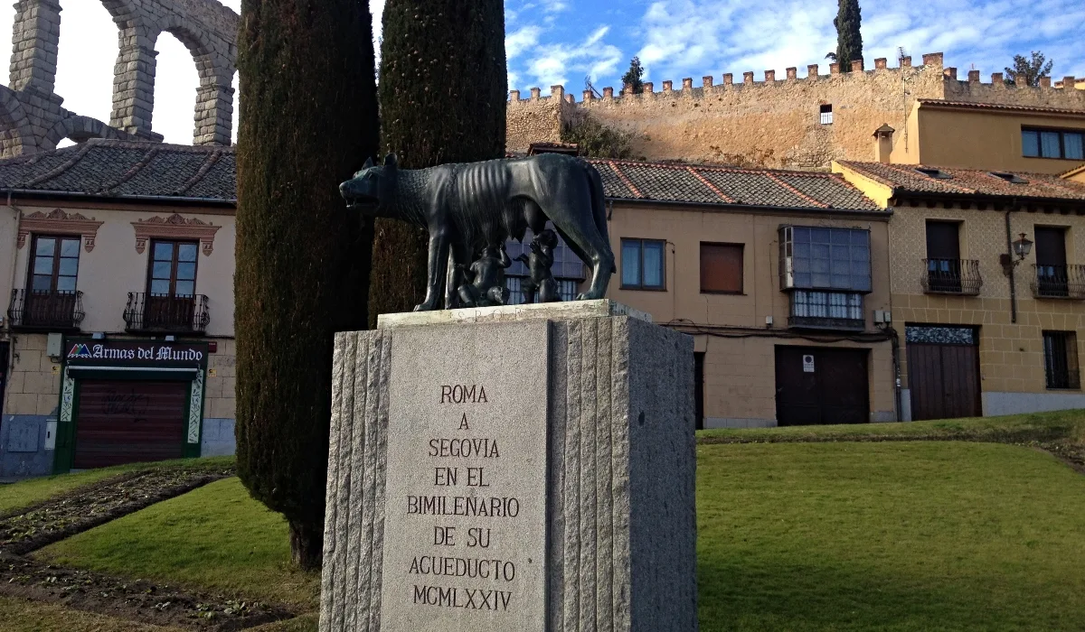 Escultura de la Loba Capitolina en el Azoguejo de Segovia, con la muralla medieval al fondo