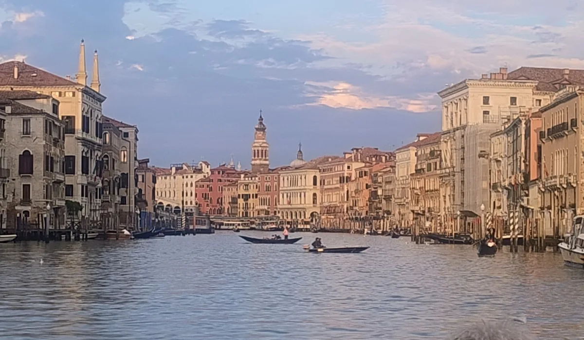 Vista panorámica del Gran Canal de Venecia al atardecer, con palacios históricos a ambos lados y barcas navegando por el centro de la ciudad