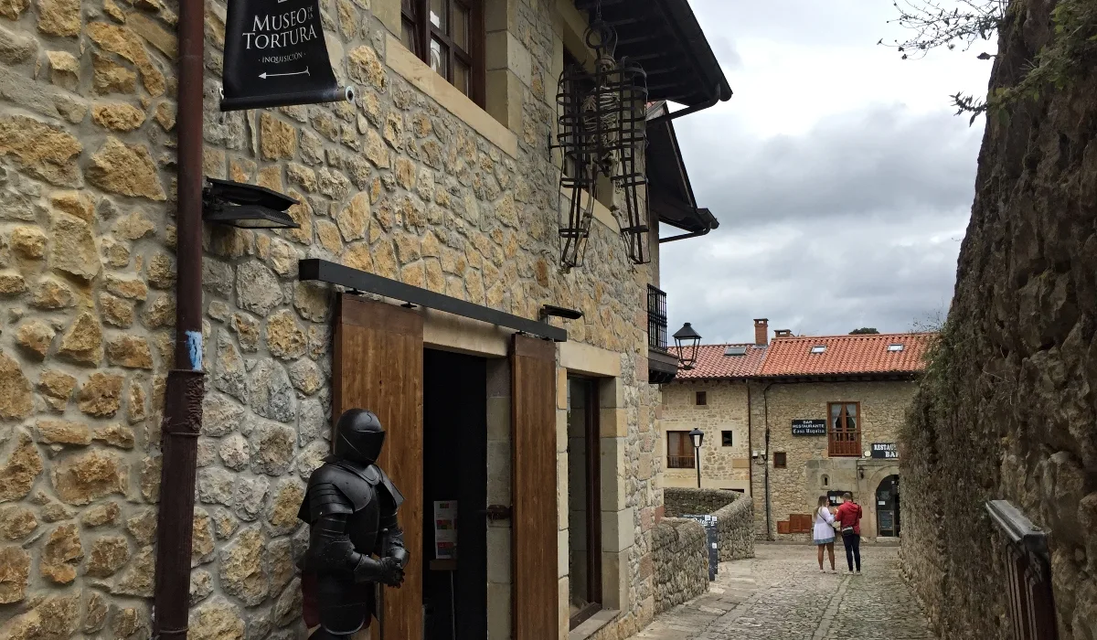 Entrada del Museo de la Tortura en Santillana del Mar, edificio de piedra en calle empedrada del casco histórico