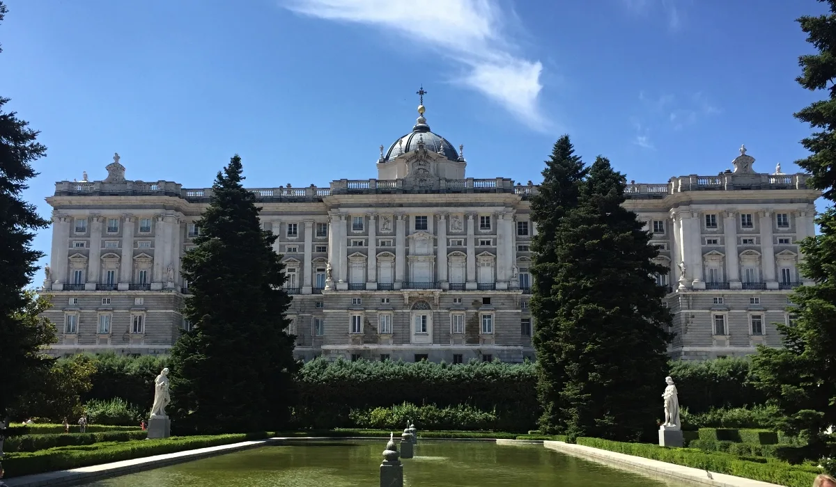 Fachada principal del Palacio Real de Madrid vista desde los jardines de Sabatini con estanque y estatuas en primer plano