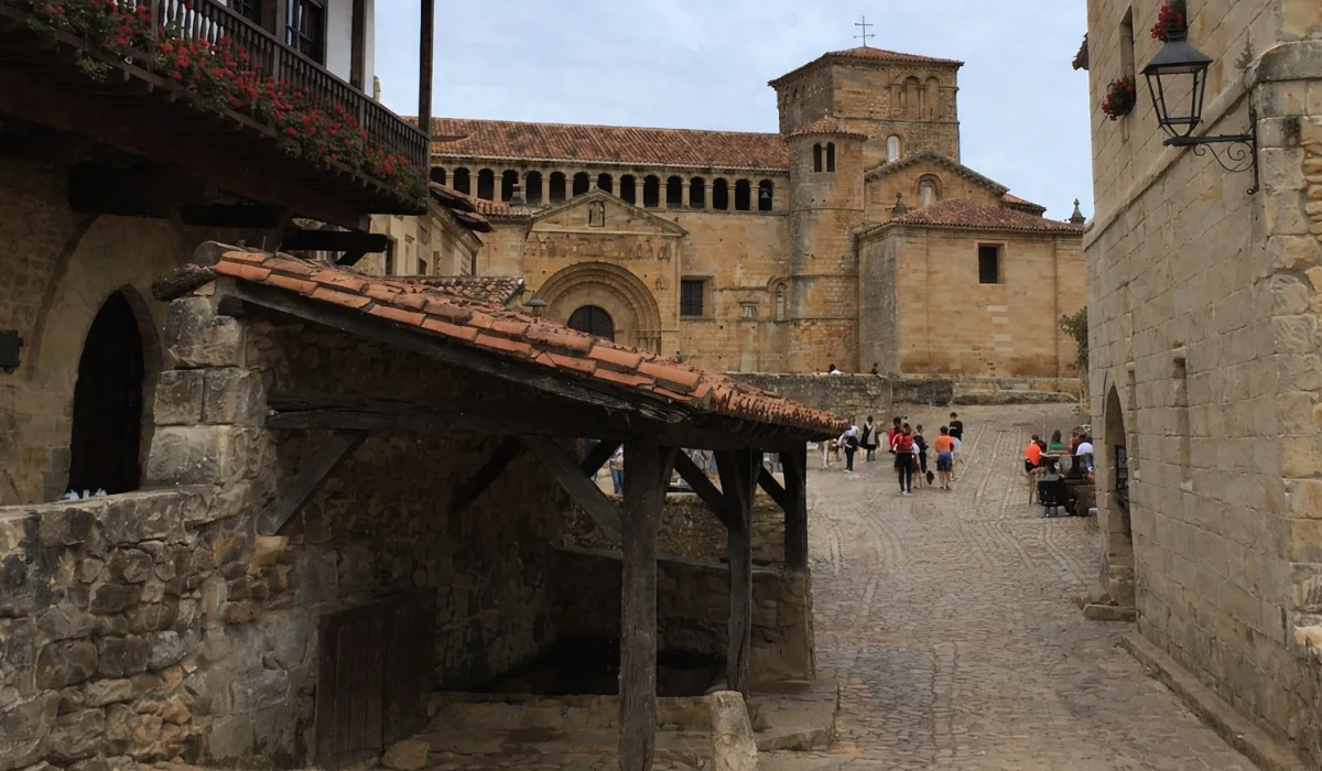 Calle empedrada de Santillana del Mar con la Colegiata de Santa Juliana al fondo y arquitectura medieval de piedra