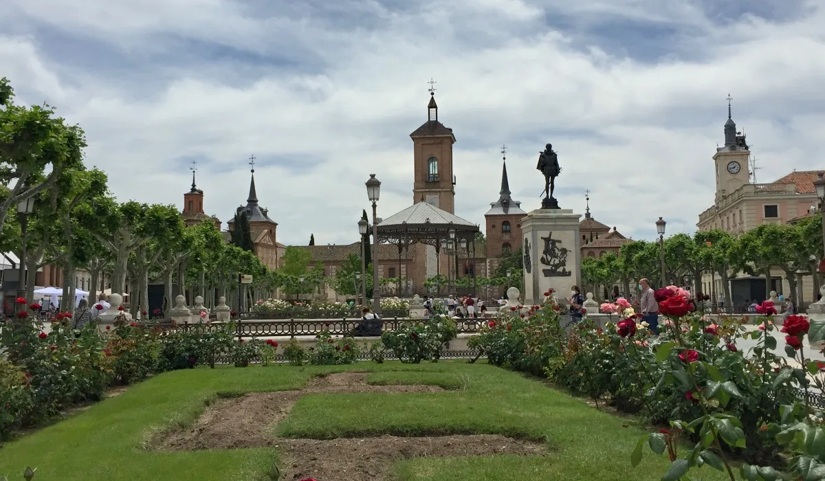 Plaza de Cervantes en Alcalá de Henares con jardines, estatua central y edificios históricos