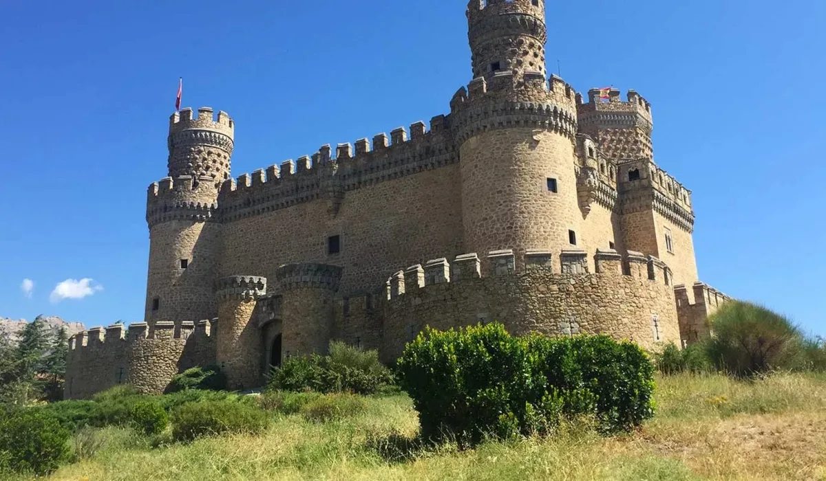 Vista del Castillo de Manzanares El Real, fortaleza medieval de la Comunidad de Madrid rodeada de murallas y torres bajo un cielo despejado