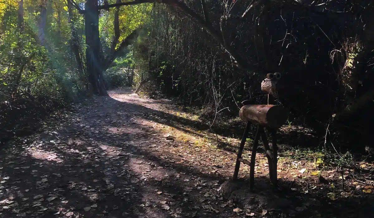 Escultura de un ciervo de madera entre los árboles de la Senda Mágica de Arroyomolinos