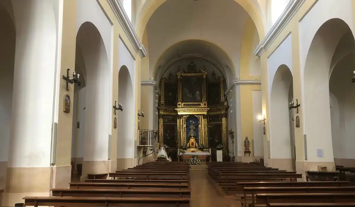 Interior de la Iglesia de Santa María del Manto de Riaza, con bancos de madera, arcos y retablo mayor dorado